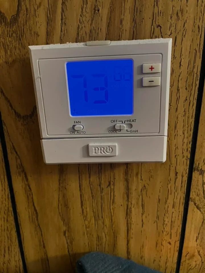 Old programmable thermostat serviced during heating maintenance
